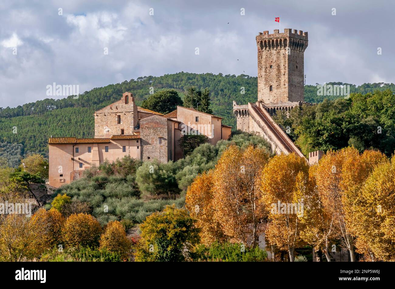 La bella Rocca di Vicopisano, Italia, con la bandiera bianca e rossa di Pisa, circondata dalla natura dipinta nei colori autunnali Foto Stock