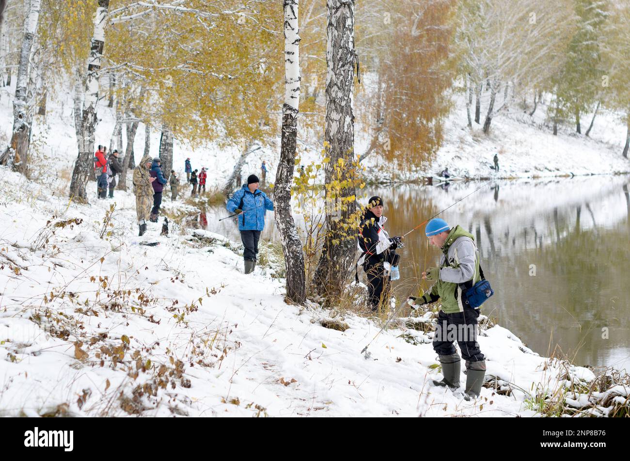 Le persone sono pescatori su entrambe le rive innevate del lago alla concorrenza in Russia nella foresta Foto Stock
