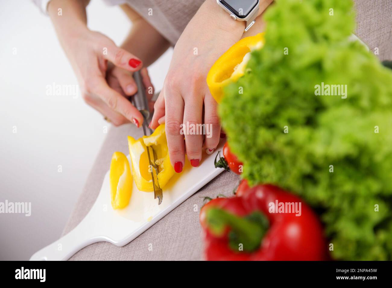 l'adulto insegna al bambino a tagliare le verdure madre aiuta il figlio a tagliare il peperone giallo primo piano mani coltello porcellana whiteboard verdure sane primi passi in cucina formazione Foto Stock