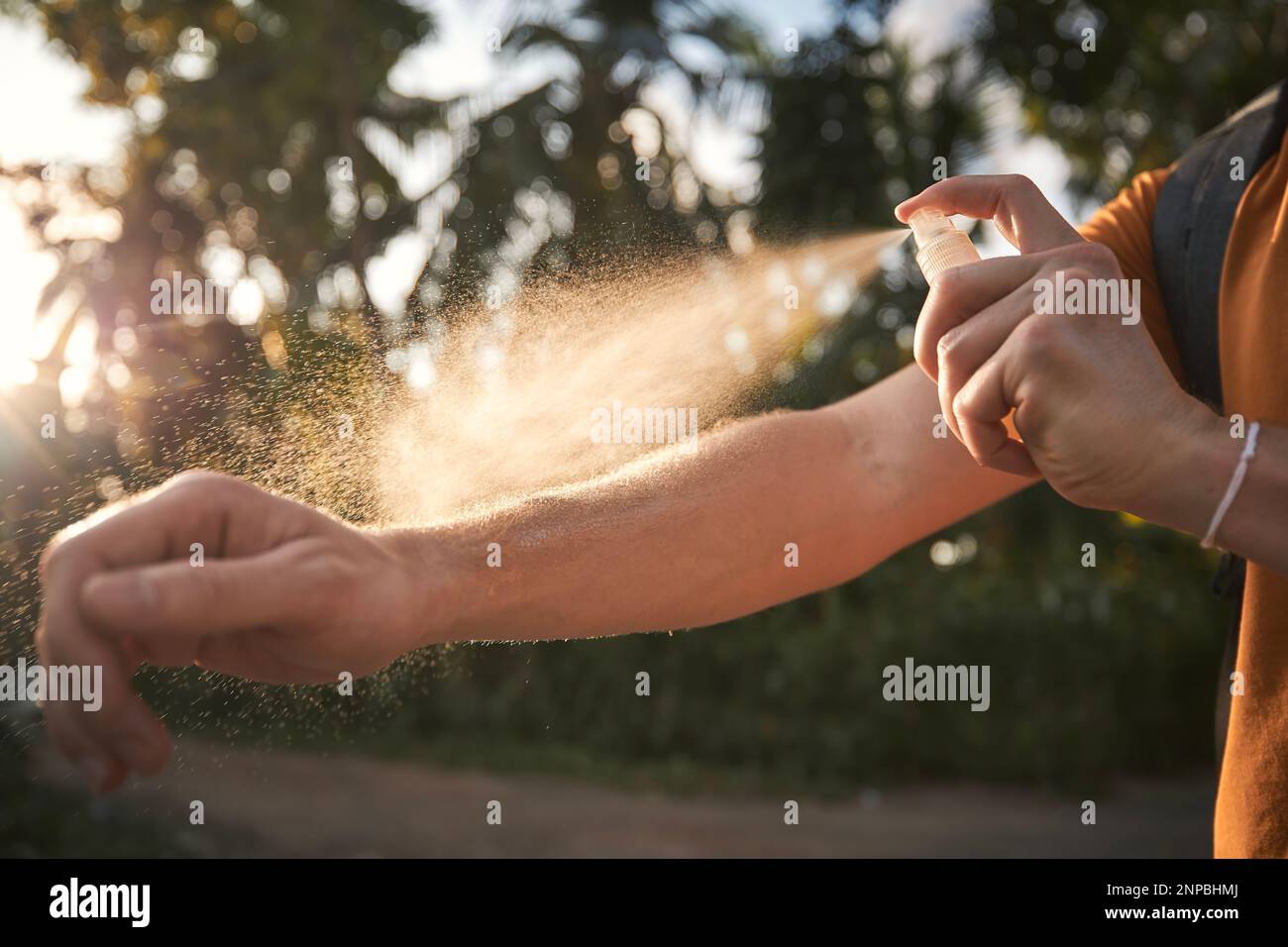 L'uomo sta applicando repellente per insetti sulla sua mano contro le palme. Prevenzione contro morso di zanzara in destinazione tropicale. Foto Stock