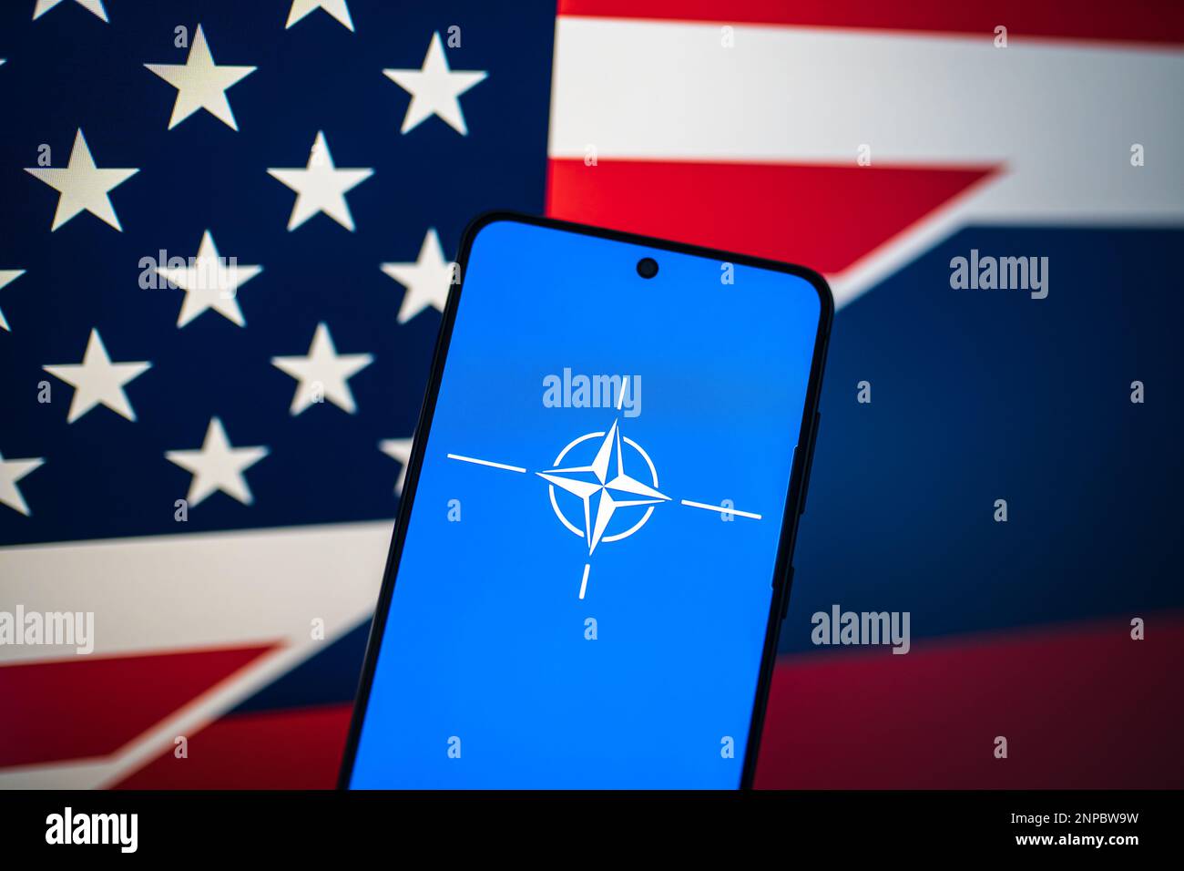 Bandiera della NATO al telefono con bandiera degli Stati Uniti e bandiera russa sullo sfondo. Swansea, Regno Unito - 21 febbraio 2023. Foto Stock