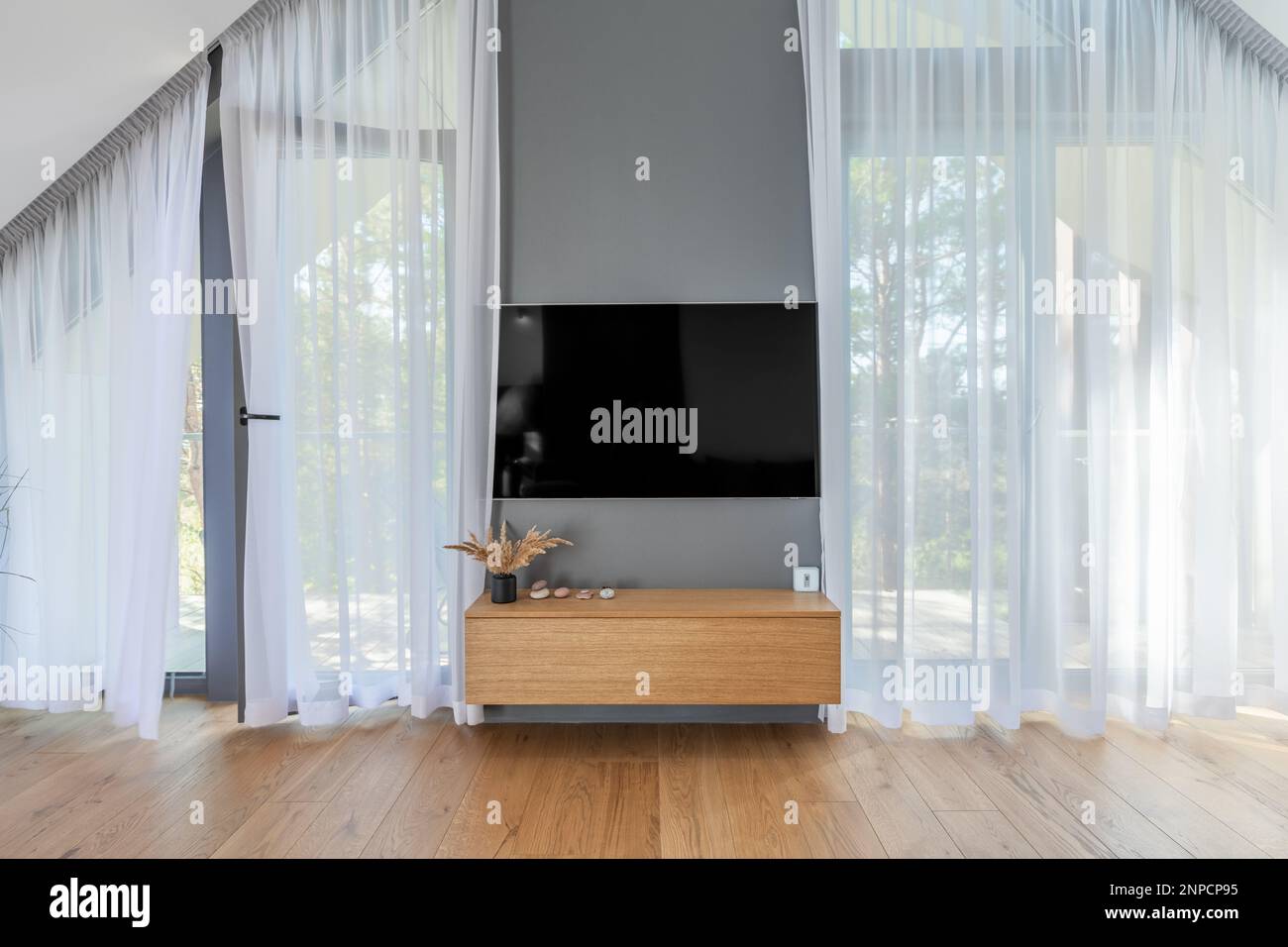 L'elegante e spazioso design degli interni di lusso del soggiorno con schermo TV, tende in un moderno arredamento di casa. Soggiorno moderno Foto Stock