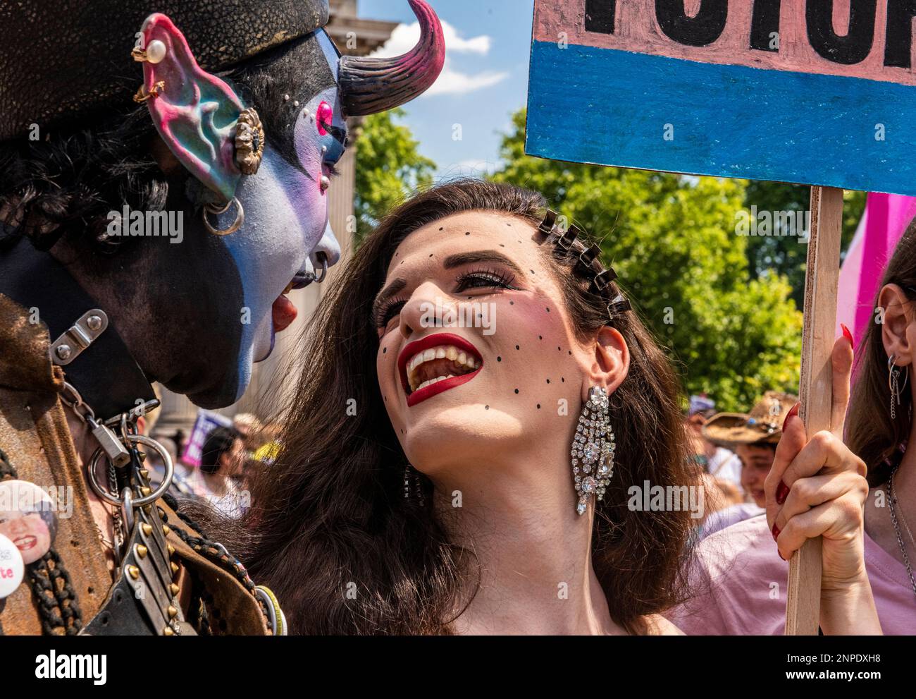 Due membri della comunità LGBTQ+ con volti fortemente dipinti e composti sorridono e parlano protestando contro la mancanza di diritti e assistenza sanitaria per le persone transgender. Foto Stock