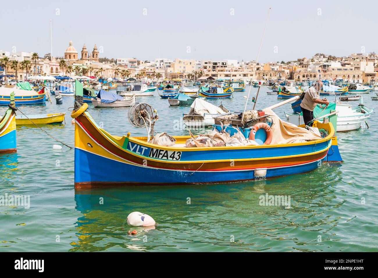 Un pescatore porta la sua barca luzzu fuori dal porto di Marsaxlokk a Malta. Foto Stock