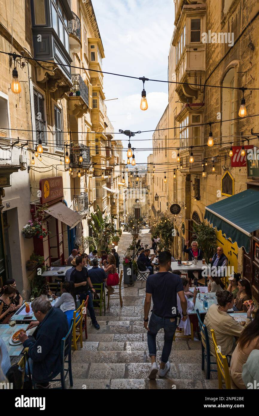 Le luci si trovano sui gradini pieni di turisti che mangiano fuori da un famoso ristorante a la Valletta a Malta. Foto Stock