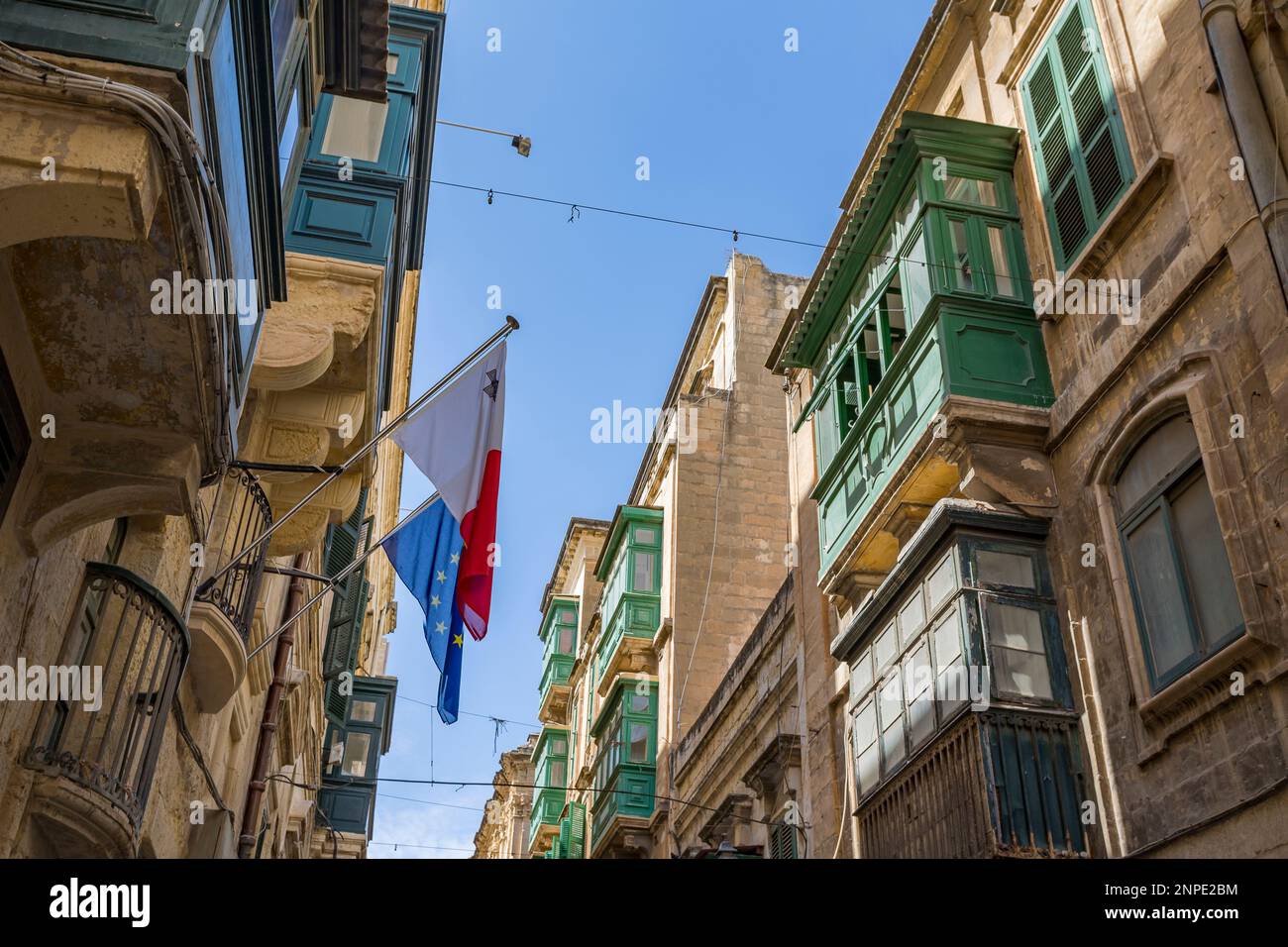 Le bandiere di Malta e dell'Unione europea si trovano sopra una strada colorata nella capitale maltese di la Valletta. Foto Stock