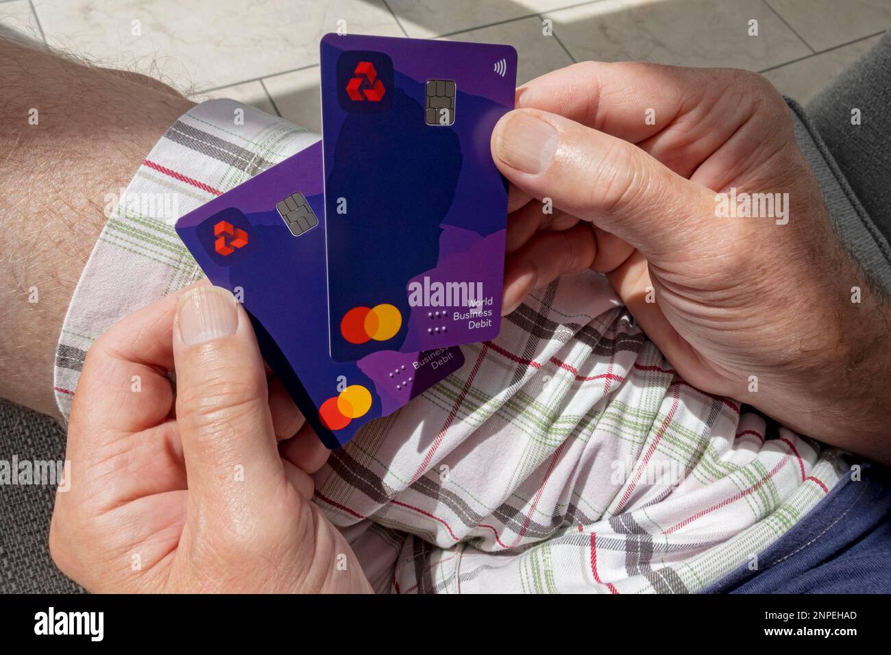 Primo piano di un uomo in possesso della carta di debito contactless Business della banca Natwest. Foto Stock