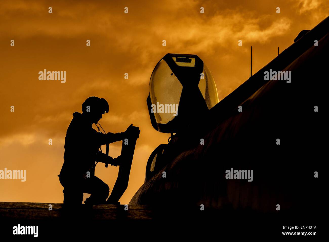 Il pilota da combattimento sale a bordo del suo intercettore da jet fighter per una missione di addestramento al tramonto. Drammatica Silhouette di pilota eroe in preparazione per la guerra Foto Stock