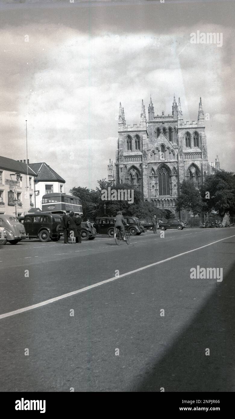 Circa 1950 anni, storico, York, Inghilterra, Regno Unito, mostra la grande cattedrale gotica, conosciuta come York Minster. Auto dell'epoca parcheggiate e un autobus a due piani che va a Leeds, con una pubblicità per la Barnsley Brewery. Autista di autobus e conduttore femmina che chiacchierano all'esterno con il supervisore. Foto Stock