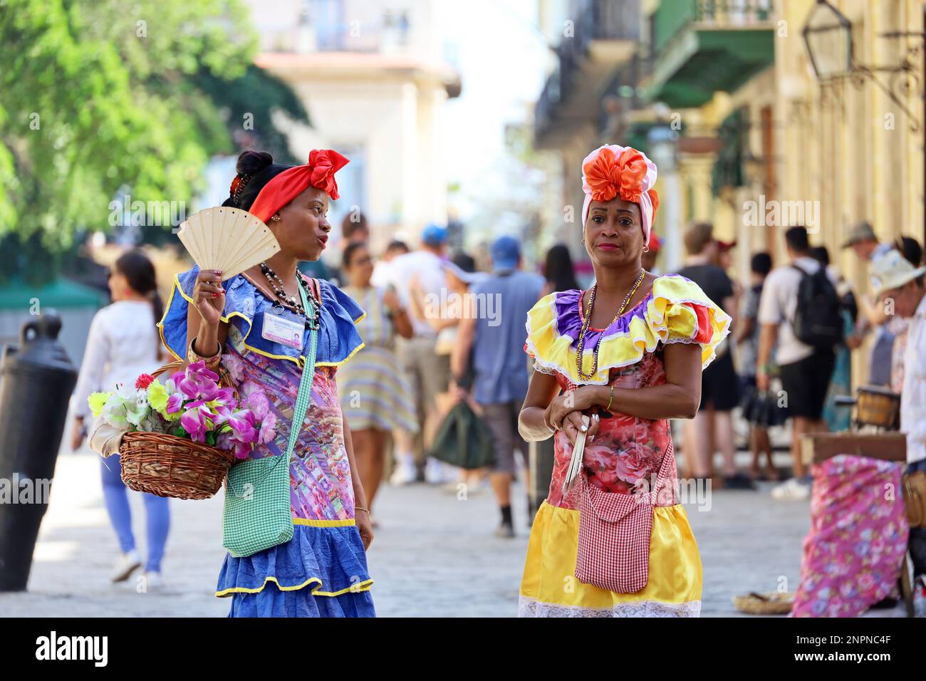 Le donne cubane in abiti tradizionali chiamati 'Costumbrista' mostrano i tempi coloniali sulla strada dell'Avana Vecchia su una folla di persone sullo sfondo Foto Stock