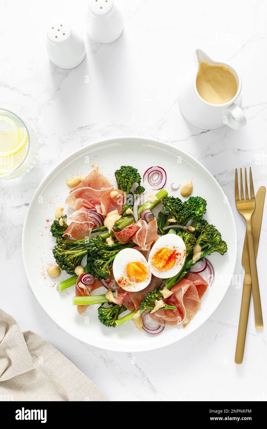 Insalata di uova di Pasqua con prosciutto e broccolini su sfondo bianco, vista dall'alto. Insalata di Pasqua con uova sode Foto Stock