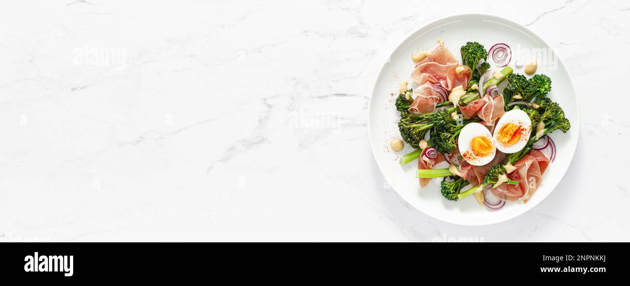 Insalata di uova di Pasqua con prosciutto e broccolini su sfondo bianco, vista dall'alto. Insalata di Pasqua con uova sode Foto Stock