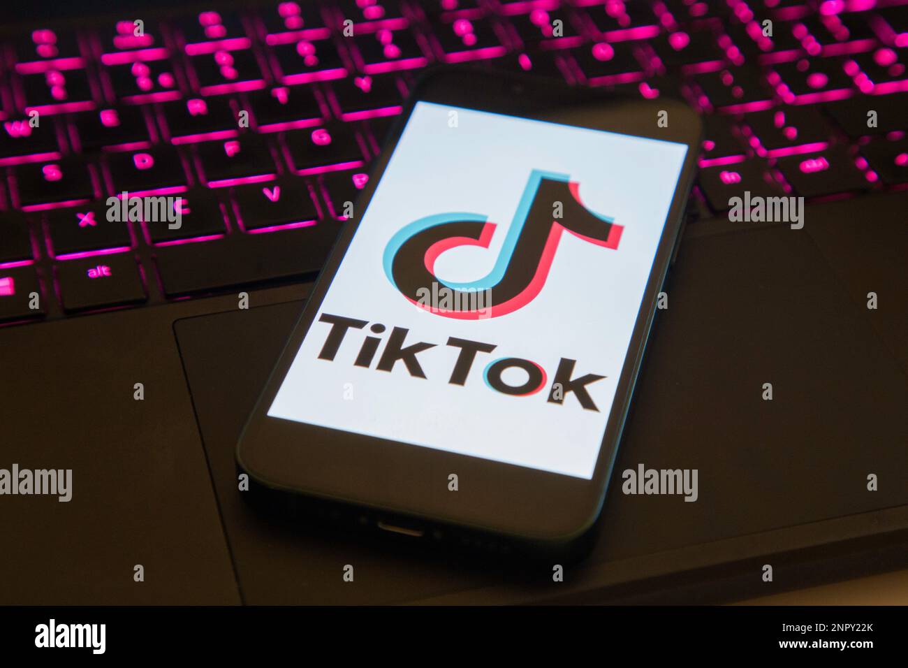 IPhone con caricamento dell'app Tik Tok seduto su un notebook illuminato Foto Stock