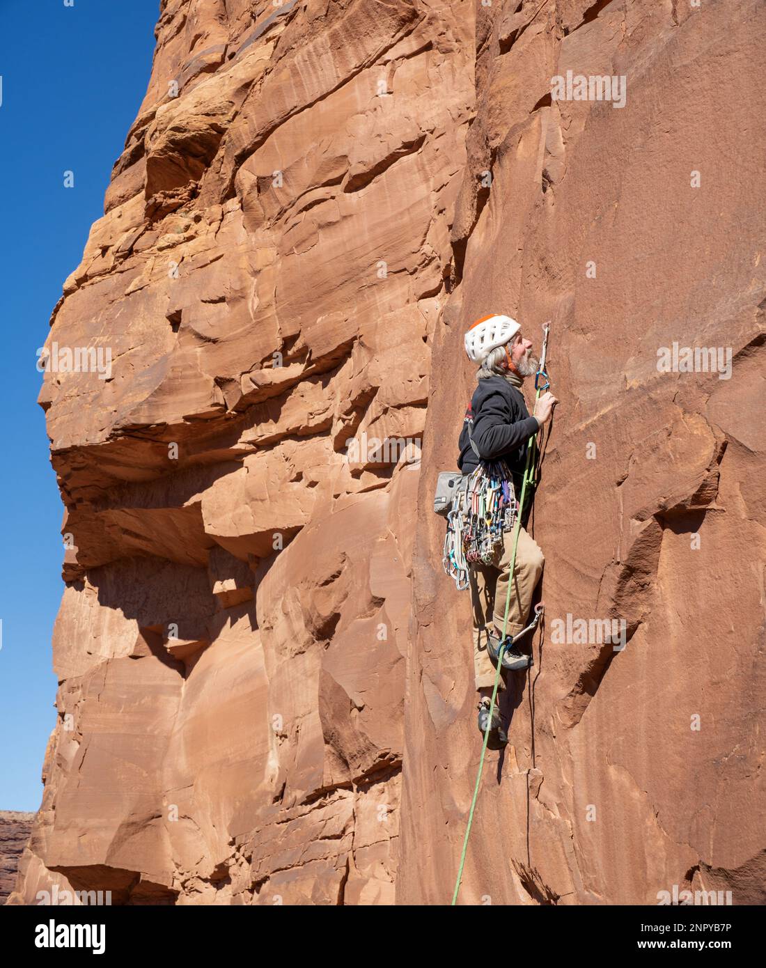 Un maschio adulto sale su una ripida parete rocciosa. Moab, Utah Foto Stock