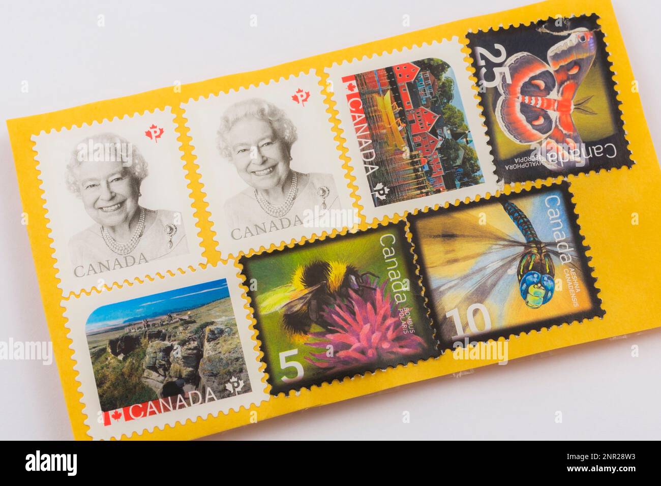 Vari francobolli canadesi su busta di carta postale gialla. Foto Stock