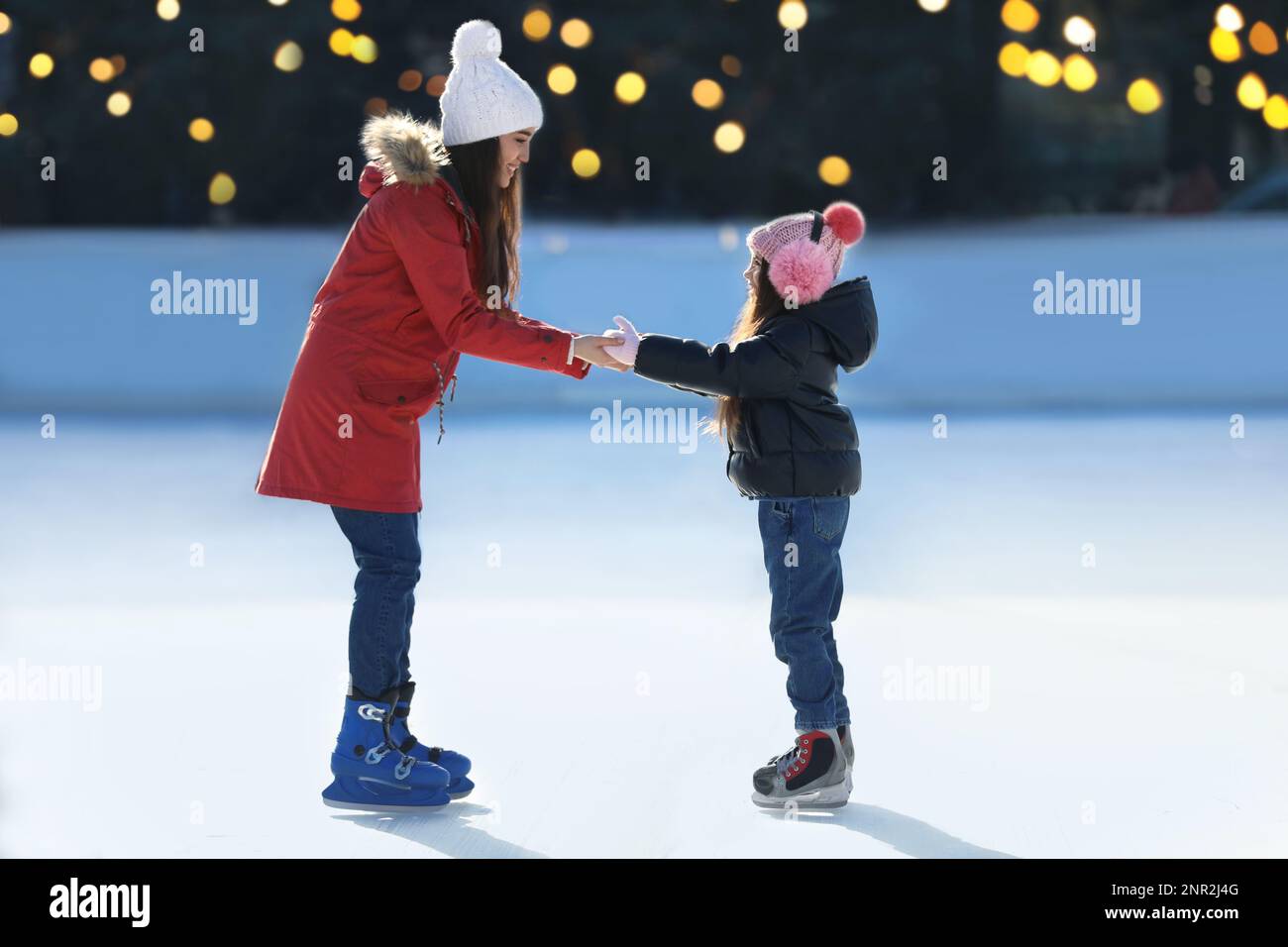 Madre e figlia trascorrono del tempo insieme alla pista di pattinaggio sul ghiaccio all'aperto Foto Stock