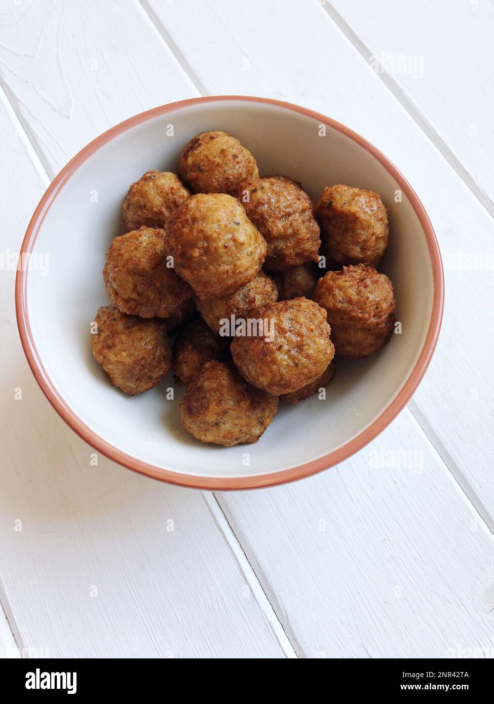 ciotola piena di polpette fritte su un tavolo di legno bianco, snack finger food Foto Stock
