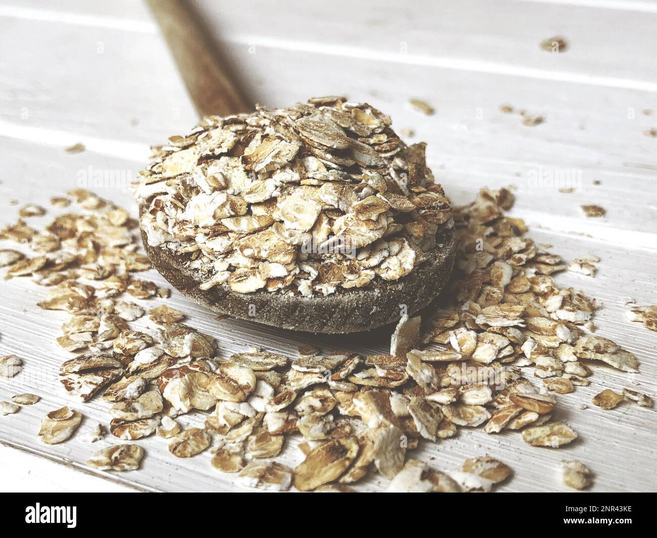 farina d'avena o avena grossolana su cucchiaio di legno su tavolo rustico con filtro vintage Foto Stock