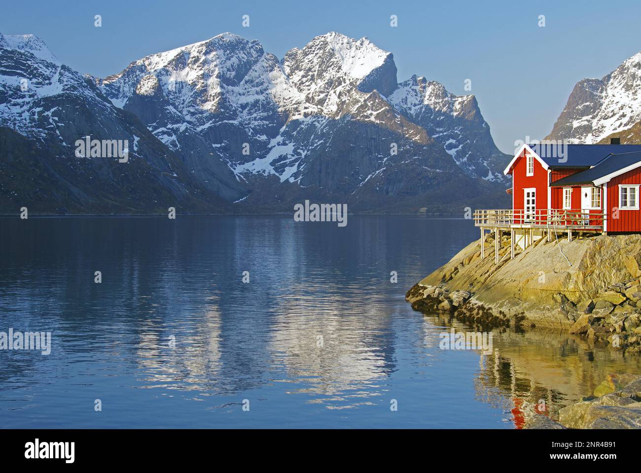 Rorbuer e alte montagne riflesse in un fiordo, vacanze, turismo, idil invernale, Hamnöy, Reinefjorden, Lofoten, Norvegia, Europa Foto Stock