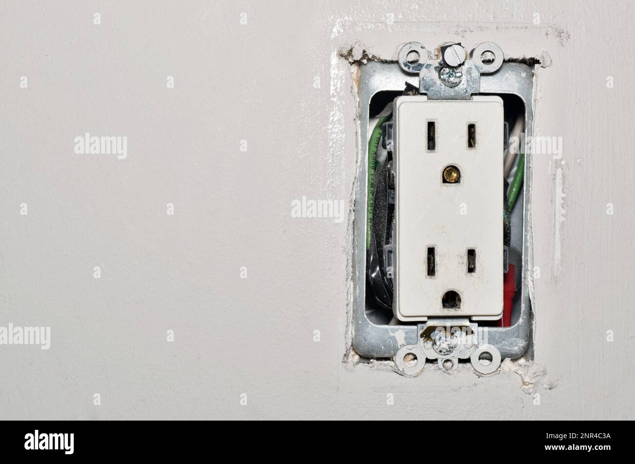 Presa di corrente pericolosa con cavi esposti senza coperchio di sicurezza della piastra a parete in plastica. Concetto di pericolo per la sicurezza della presa elettrica precedente con spazio di copia. Foto Stock