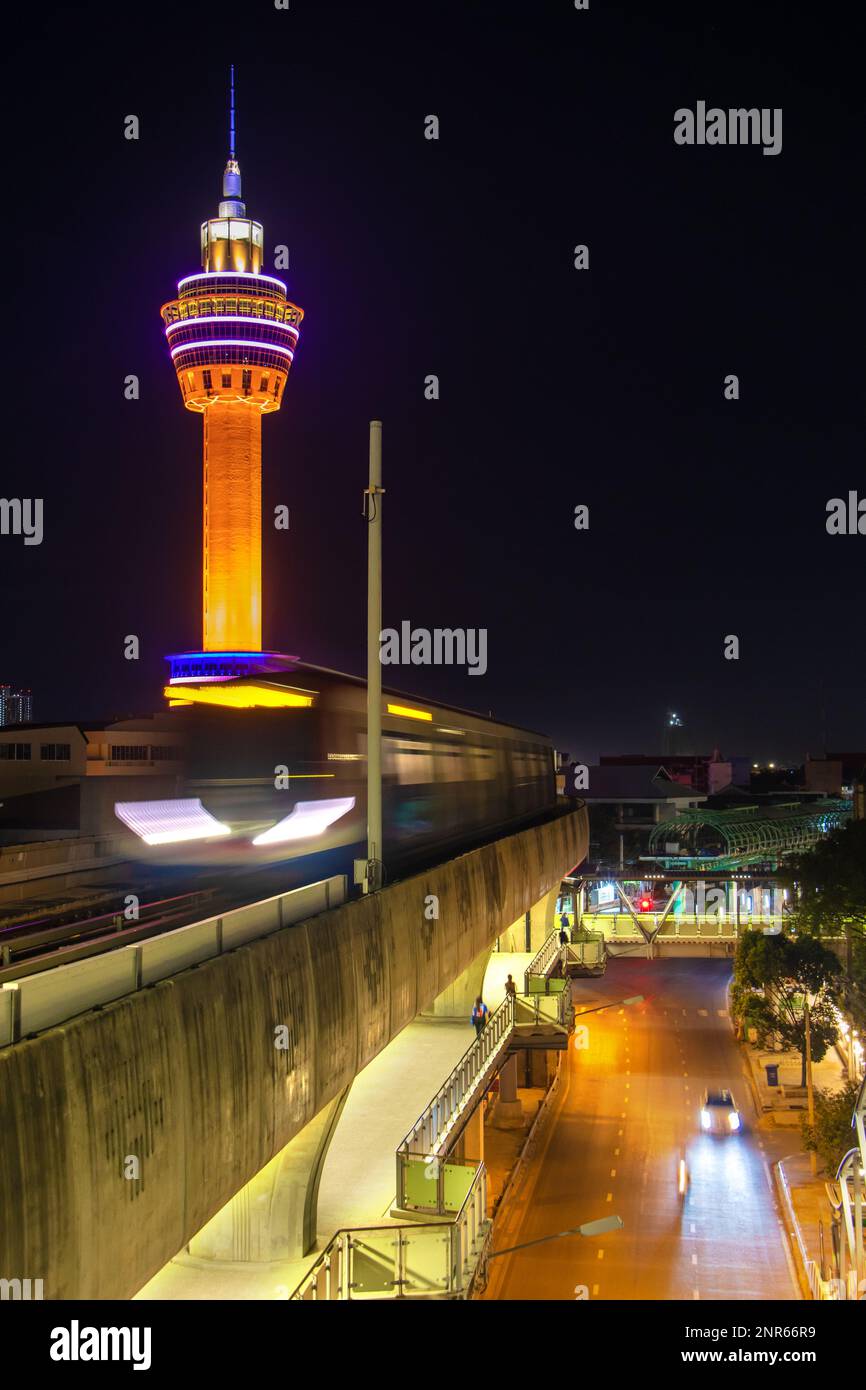 Il treno notturno viaggia sul viadotto sotto la torre di osservazione illuminata Foto Stock