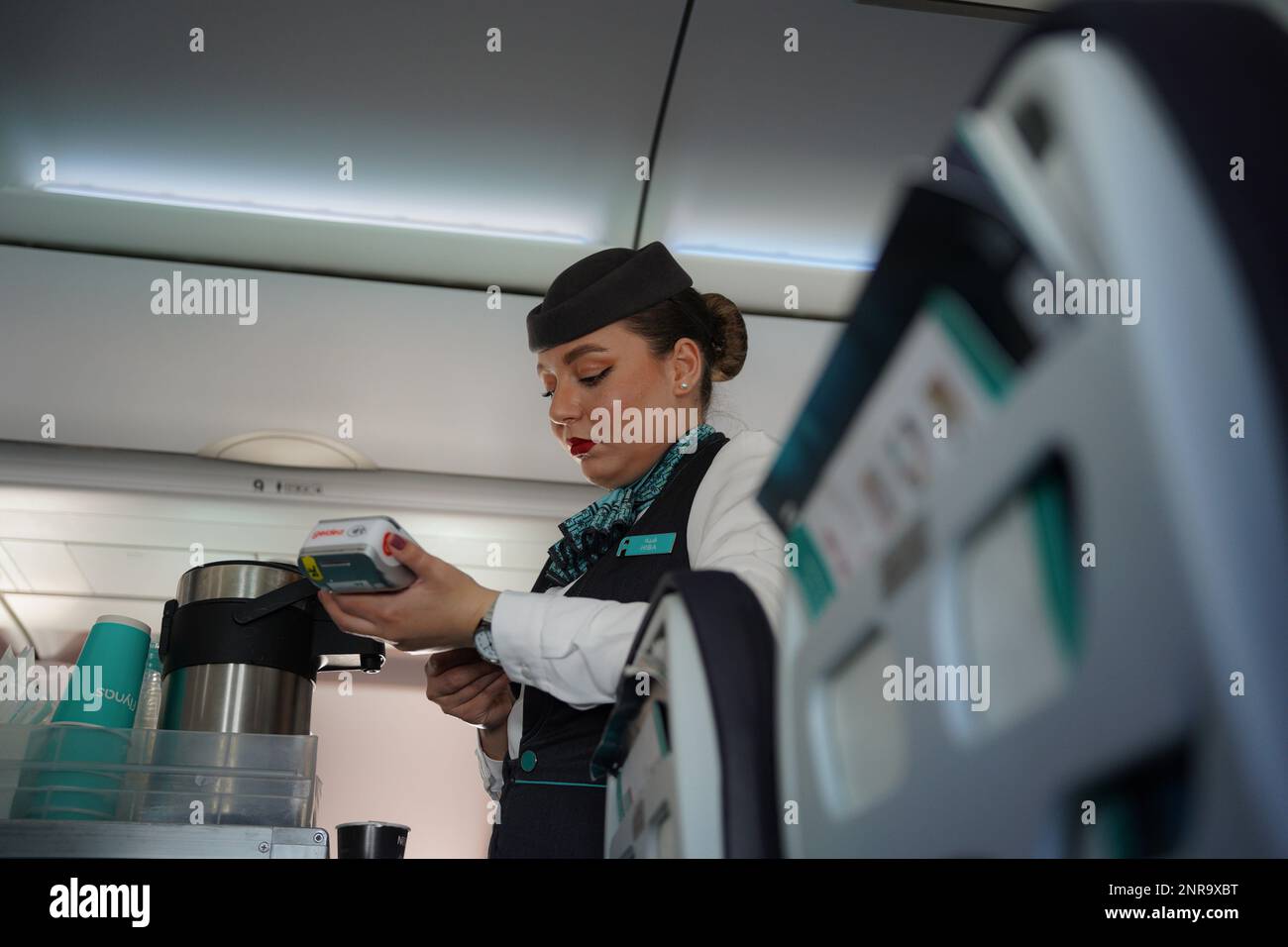 Assistente di volo o equipaggio di Flynass, una donna che lavora sull'aereo che serve cibo e bevande tradizionalmente conosciuto come una hostess dell'aria, hostess, steward, o Foto Stock