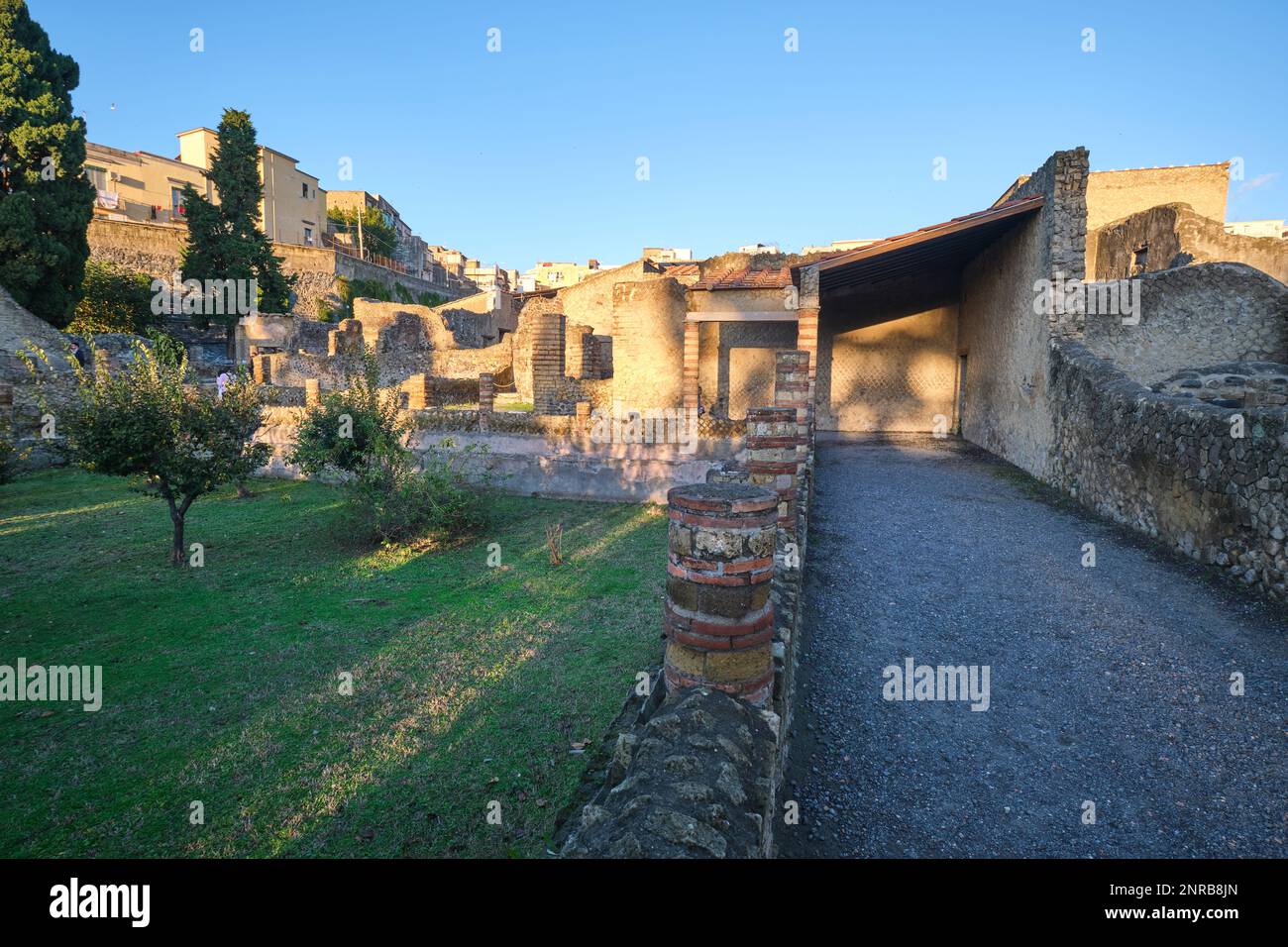 Una fila di mattoni e frammenti di colonna di pietra e un percorso. Presso la città archeologica romana in rovina, sito della città di Ercolano, vicino a Napoli, Italia. Foto Stock