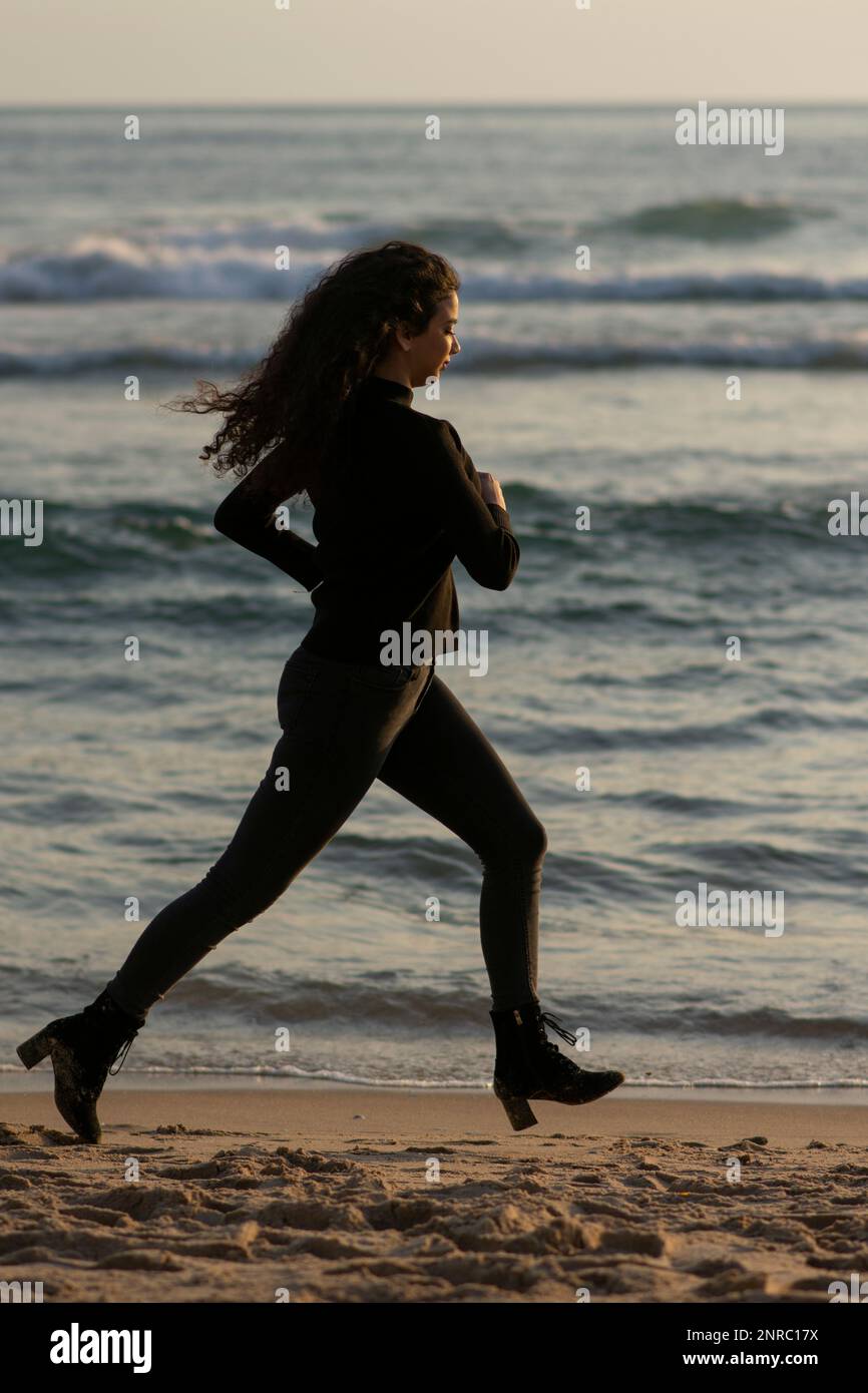 Donna che corre via sulla spiaggia Foto Stock