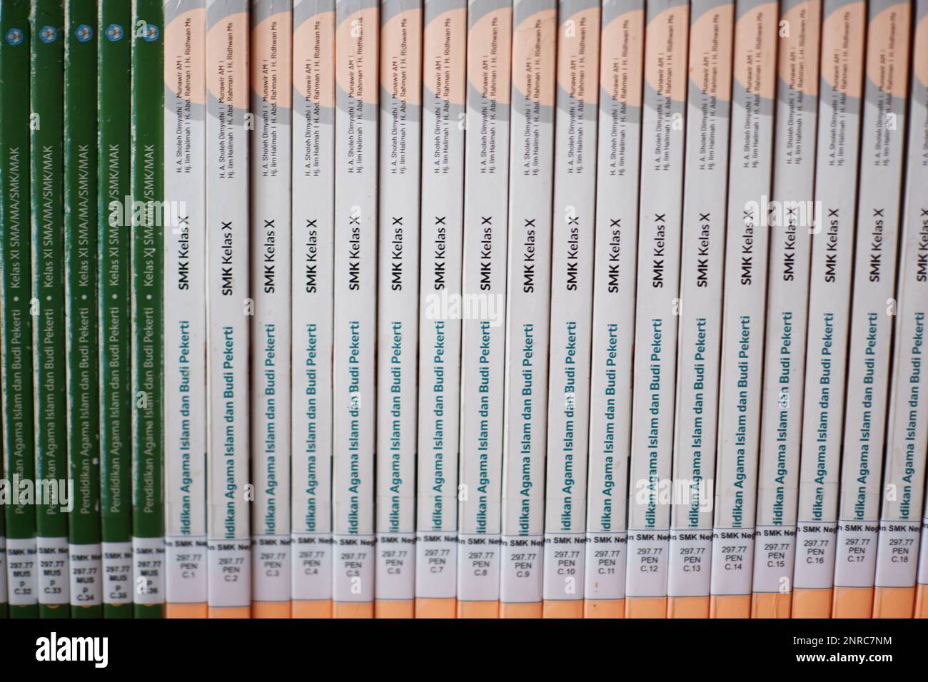 Libri di testo della scuola con copertine bianche e verdi ben sistemate, sullo scaffale della biblioteca della scuola, Desa Air Belo durante il giorno Foto Stock