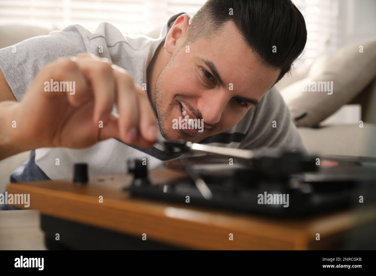 Uomo felice che usa il giradischi a casa, primo piano Foto Stock