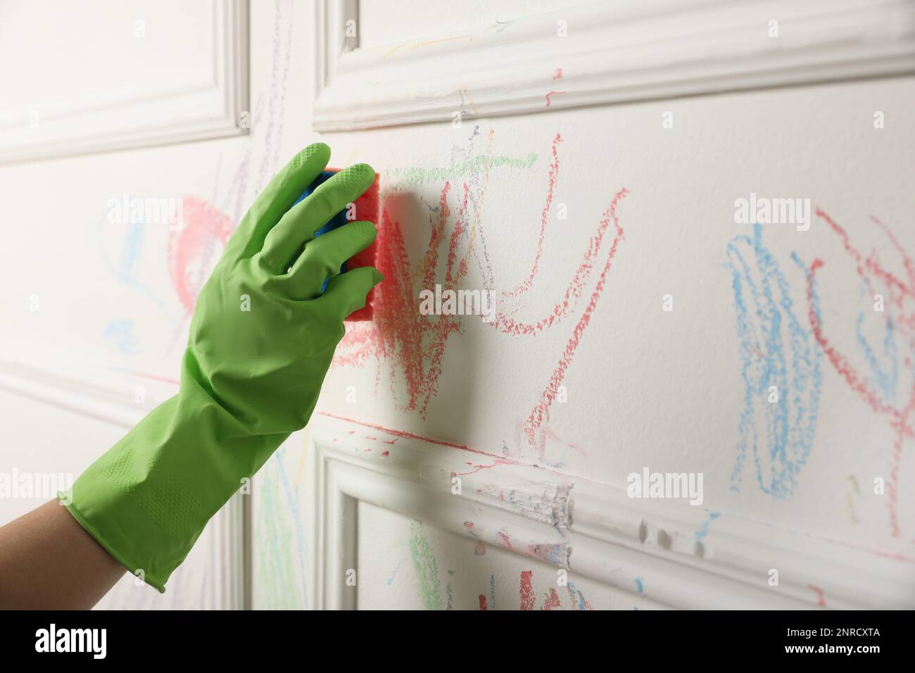 Donna che cancella il disegno del bambino dal muro bianco, primo piano Foto Stock