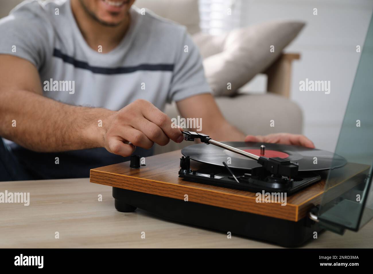 Uomo che usa giradischi al tavolo di legno all'interno, closeup Foto Stock