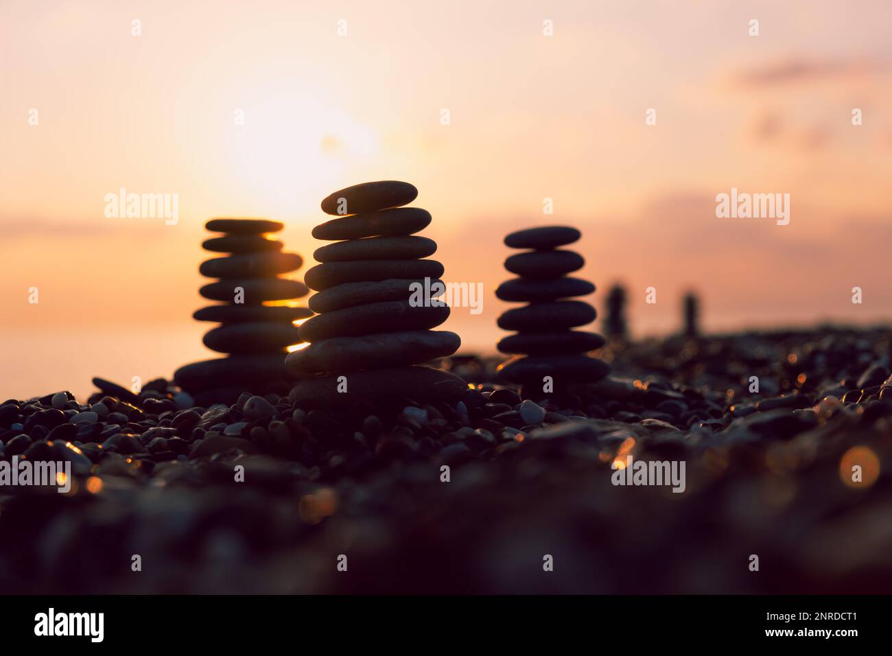 Profilo equilibrato piramidale di ciottoli sulla spiaggia al tramonto con Mare sullo sfondo. Pietre Zen sulla spiaggia di mare, meditazione, spa, armonia, calma, Foto Stock