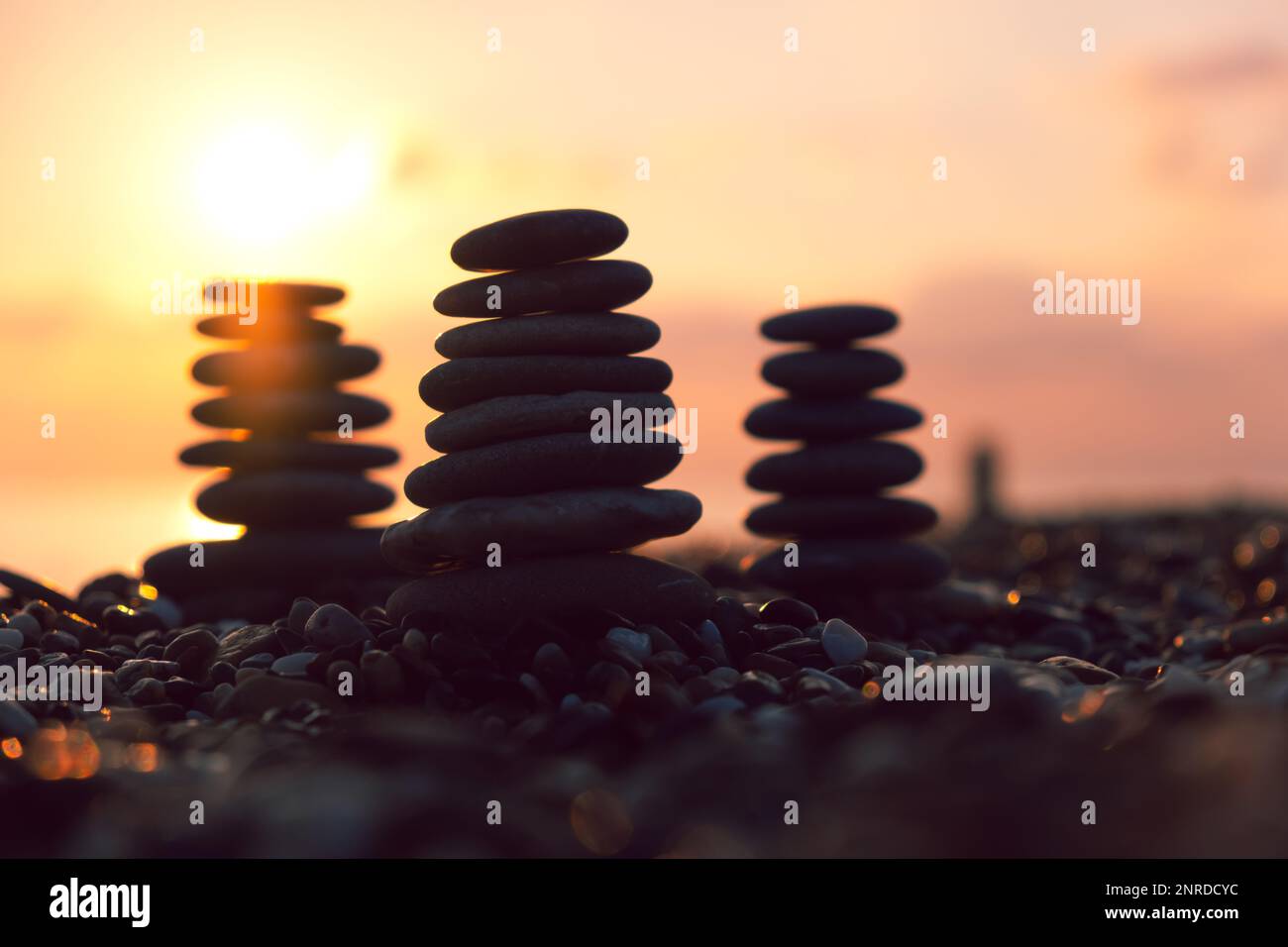 Profilo equilibrato piramidale di ciottoli sulla spiaggia al tramonto con Mare sullo sfondo. Pietre Zen sulla spiaggia di mare, meditazione, spa, armonia, calma, Foto Stock