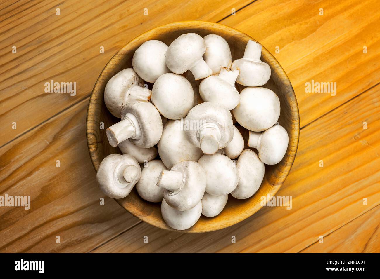 Funghi bianchi freschi champignon in ciotola di legno marrone su sfondo tavolo di legno Foto Stock