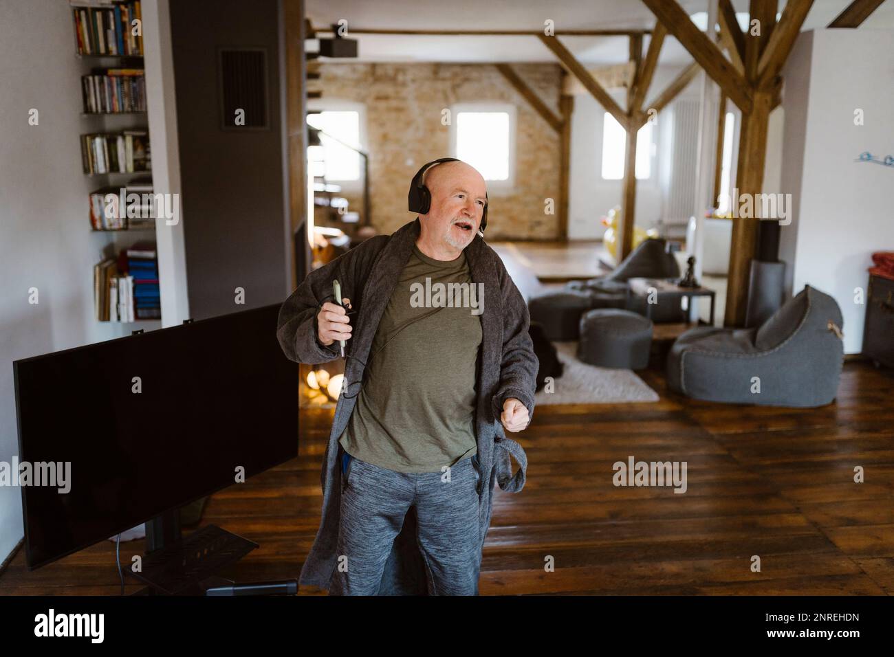 Un uomo anziano spensierato che balla mentre ascolta la musica a casa Foto Stock