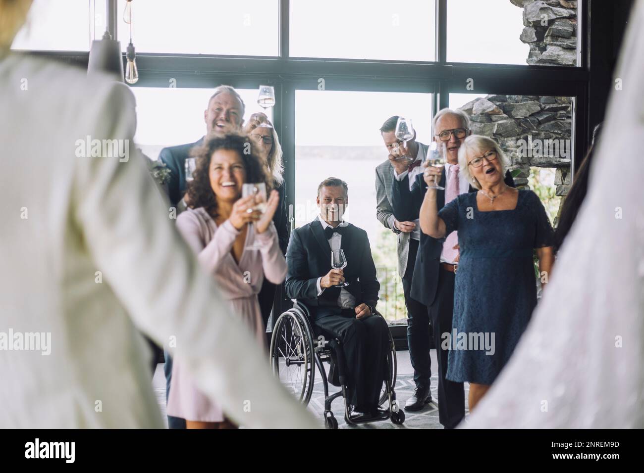 Ospiti multirazziali felici con i wineglass che allietano la coppia newlywed alla cerimonia nuziale Foto Stock