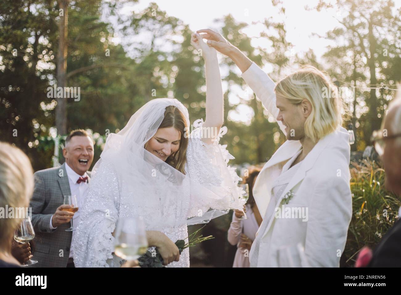 Buon sposo che tiene la mano della sposa e ballare fra gli ospiti alla celebrazione di nozze Foto Stock