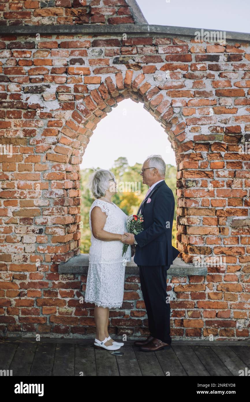 Coppia anziana in piedi faccia a faccia a finestra il giorno del matrimonio Foto Stock