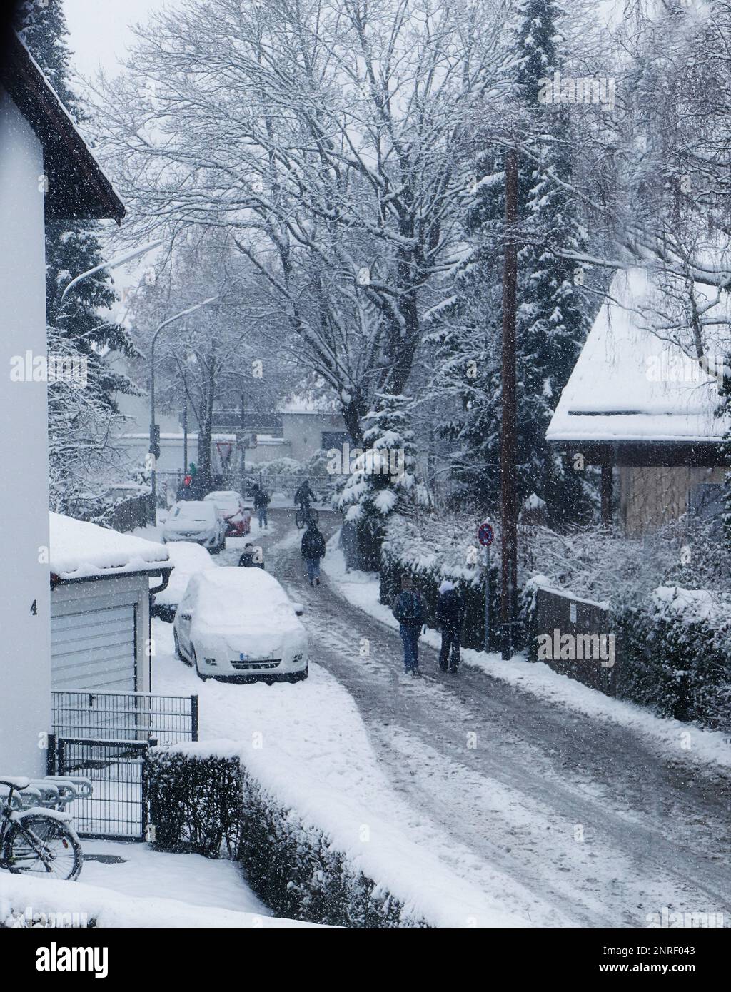 I ragazzi che camminano fuori dalla scuola a casa sotto una forte nevicata una giornata fredda di dicembre Foto Stock