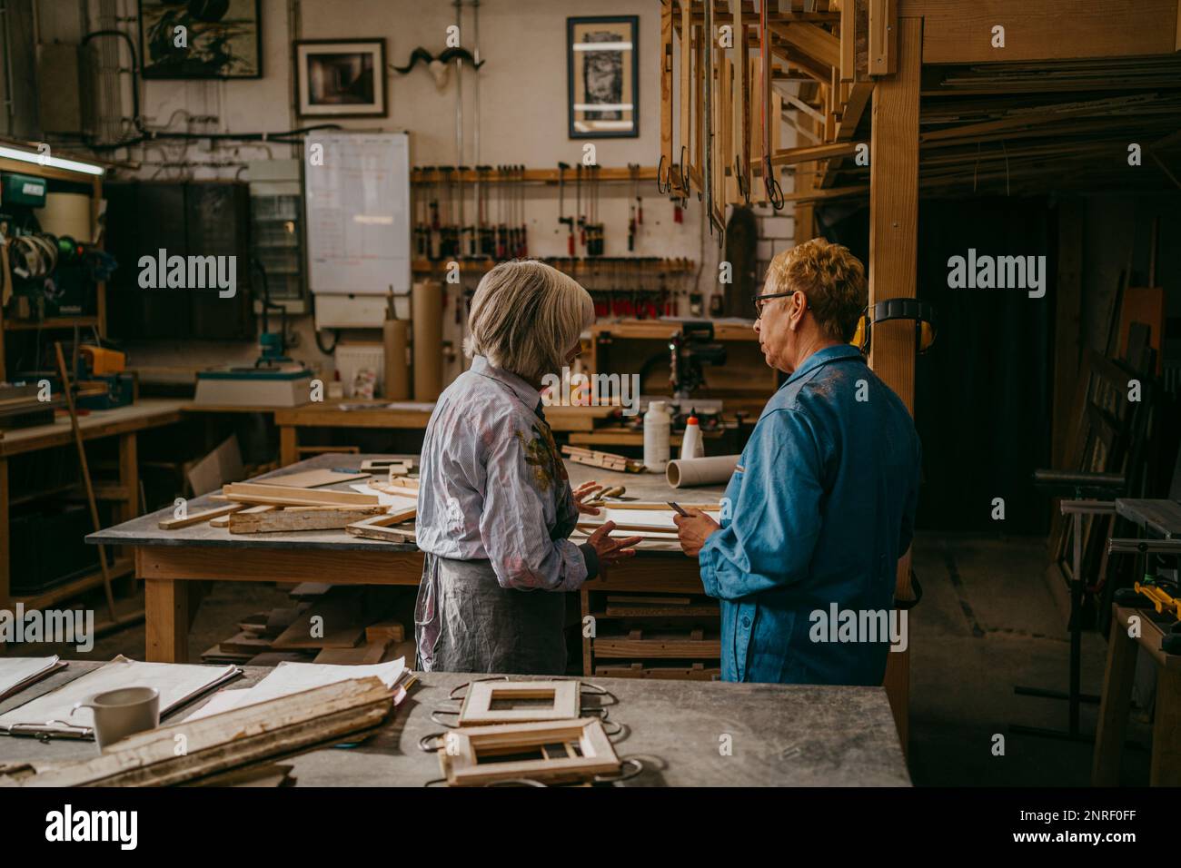 Artigiani senior che discutono insieme mentre lavorano in officina Foto Stock