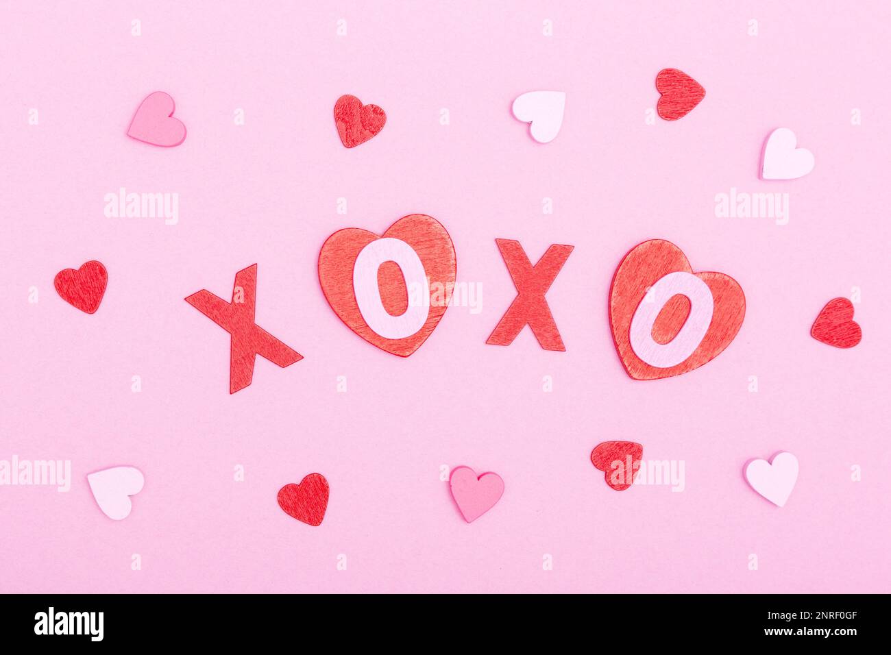 L'iscrizione xo xo da lettere e cuori di legno su sfondo rosa. Il concetto di giorno di San Valentino, amore, datazione e matrimonio. Simbolo del bacio. piatto Foto Stock