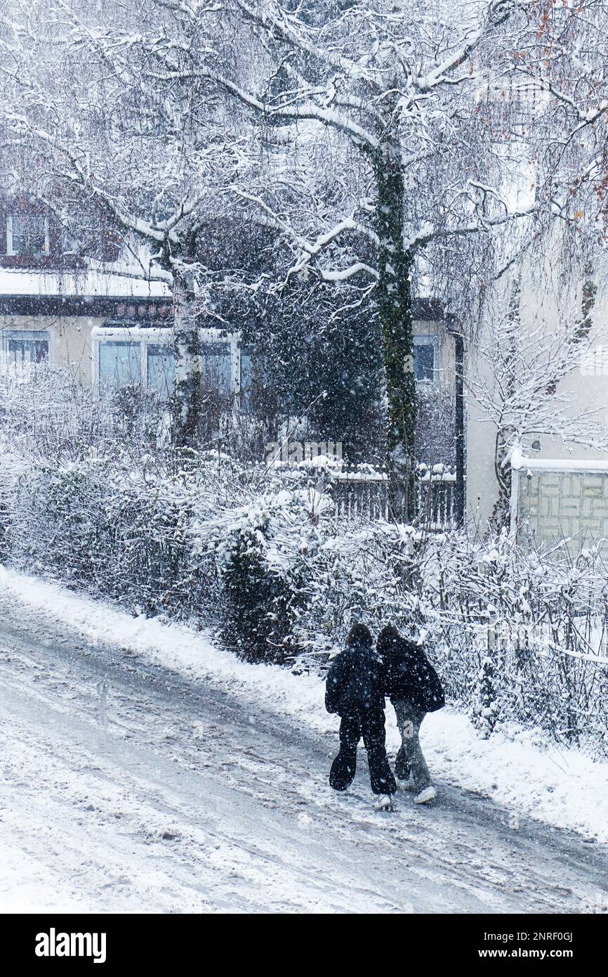 I ragazzi che camminano fuori dalla scuola a casa sotto una forte nevicata una giornata fredda di dicembre Foto Stock