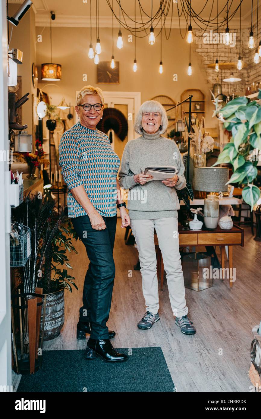Imprenditori femminili anziani felici che si levano in piedi insieme nel deposito interno domestico Foto Stock
