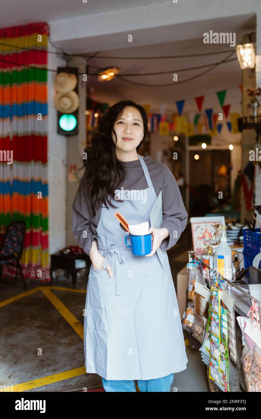 Sorridente proprietario del ristorante con la mano in tasca grembiule Foto Stock