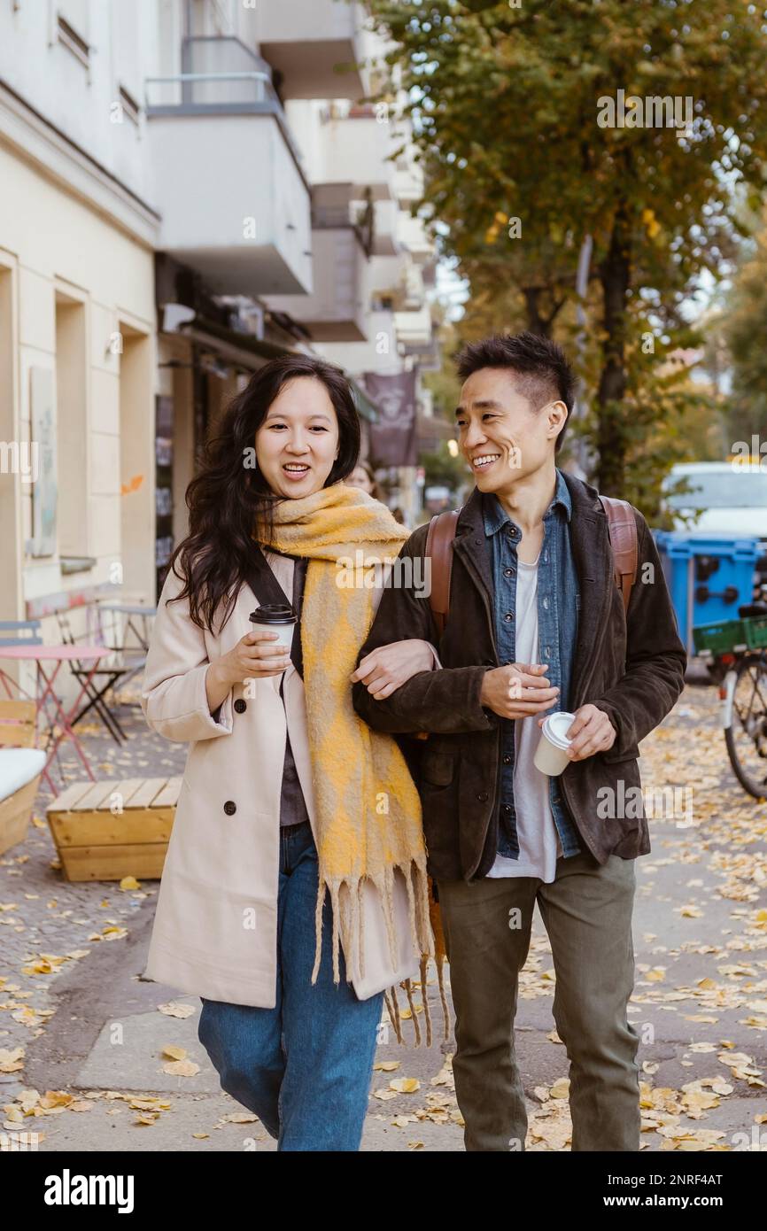 Amico maschio e femmina che parlano mentre passeggi sul marciapiede durante l'autunno Foto Stock