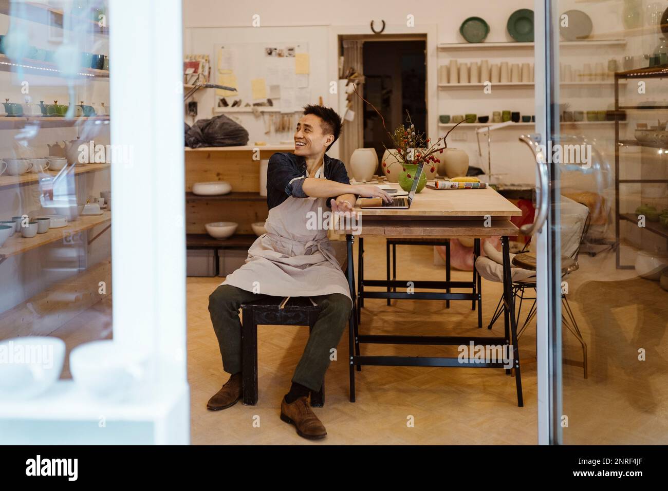 Buon artigiano che guarda via mentre si siede su una panchina a laboratorio di ceramica Foto Stock