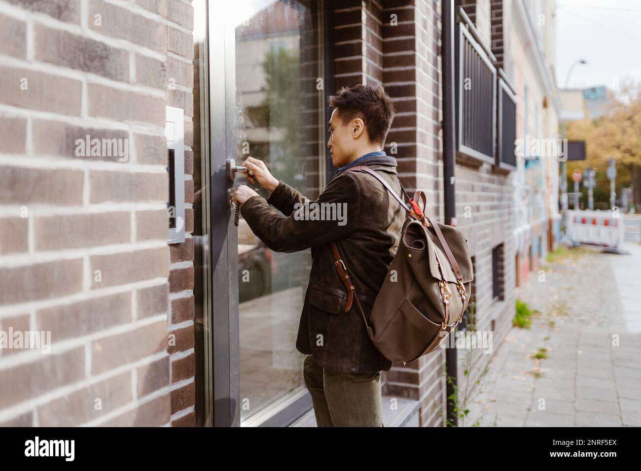 Uomo che indossa lo zaino mentre blocca la porta dell'appartamento Foto Stock