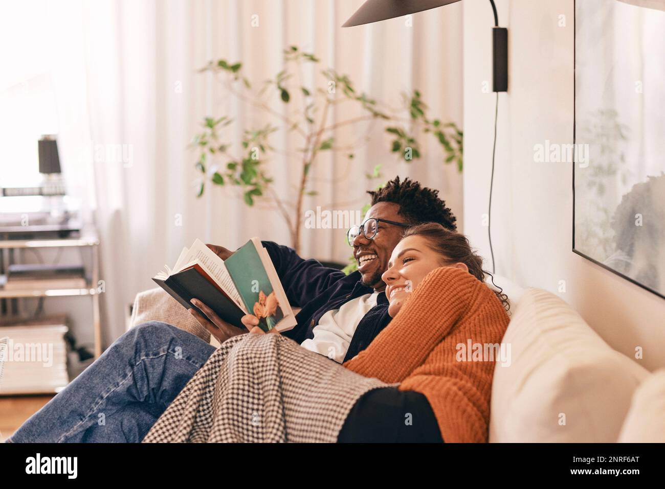 Coppia felice godendo i libri di lettura sul divano a casa Foto Stock