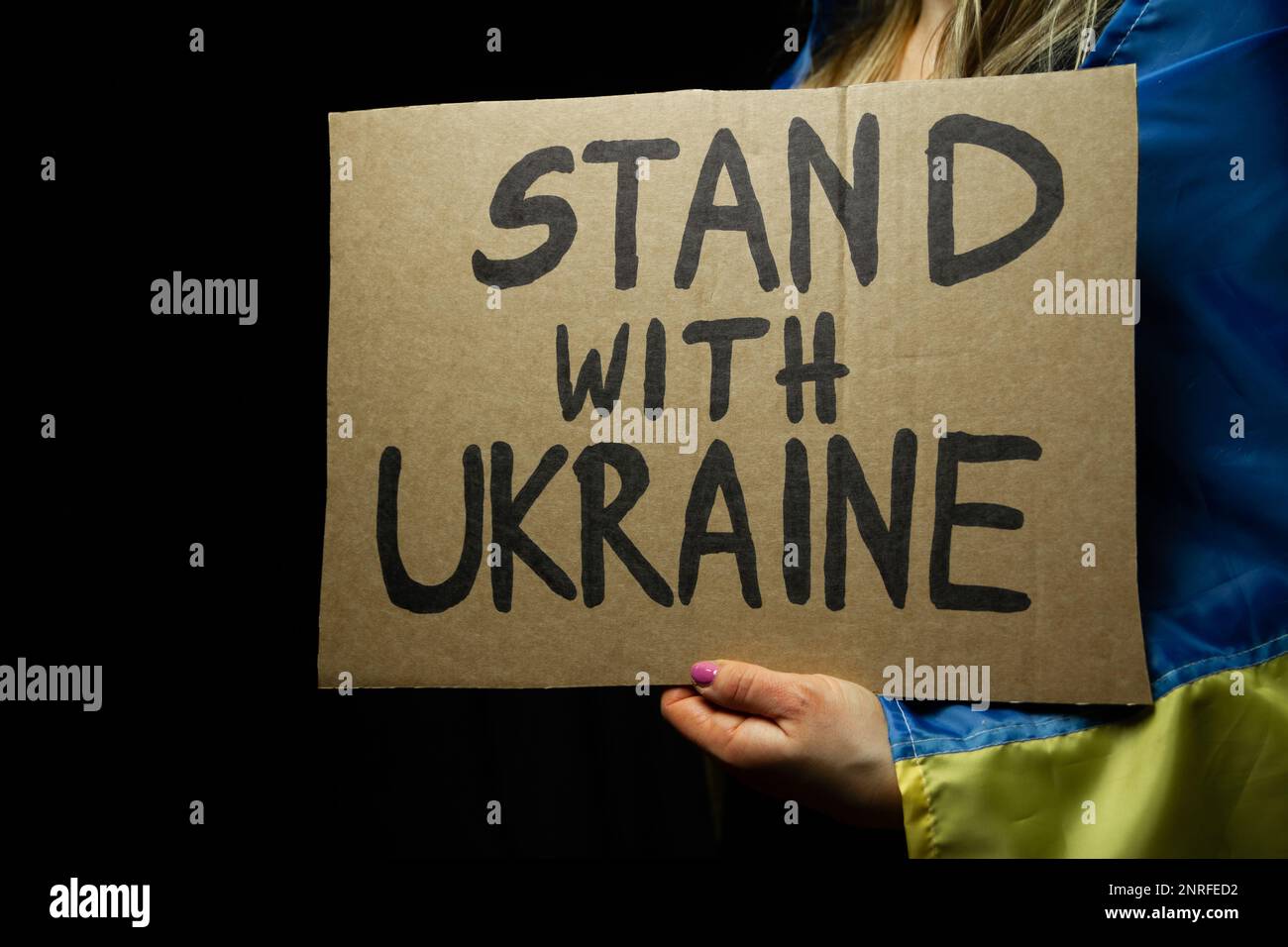Donna con bandiera Ucraina e Stand con cartello Ucraina in manifestazione di protesta contro l'invasione della Russia e la guerra contro l'Ucraina. Foto Stock